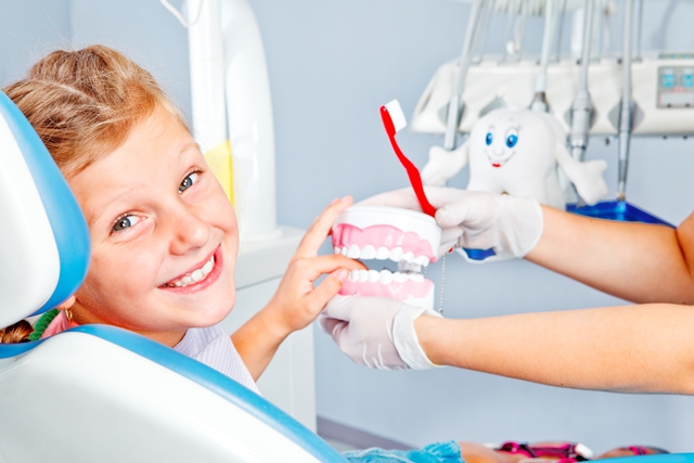 A young boy smiling at the camera while he touches a plastic mockup of a smile