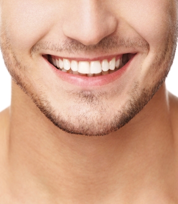 A close up of a young man with facial hair smiling