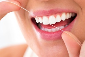 A close up of a young woman flossing her teeth