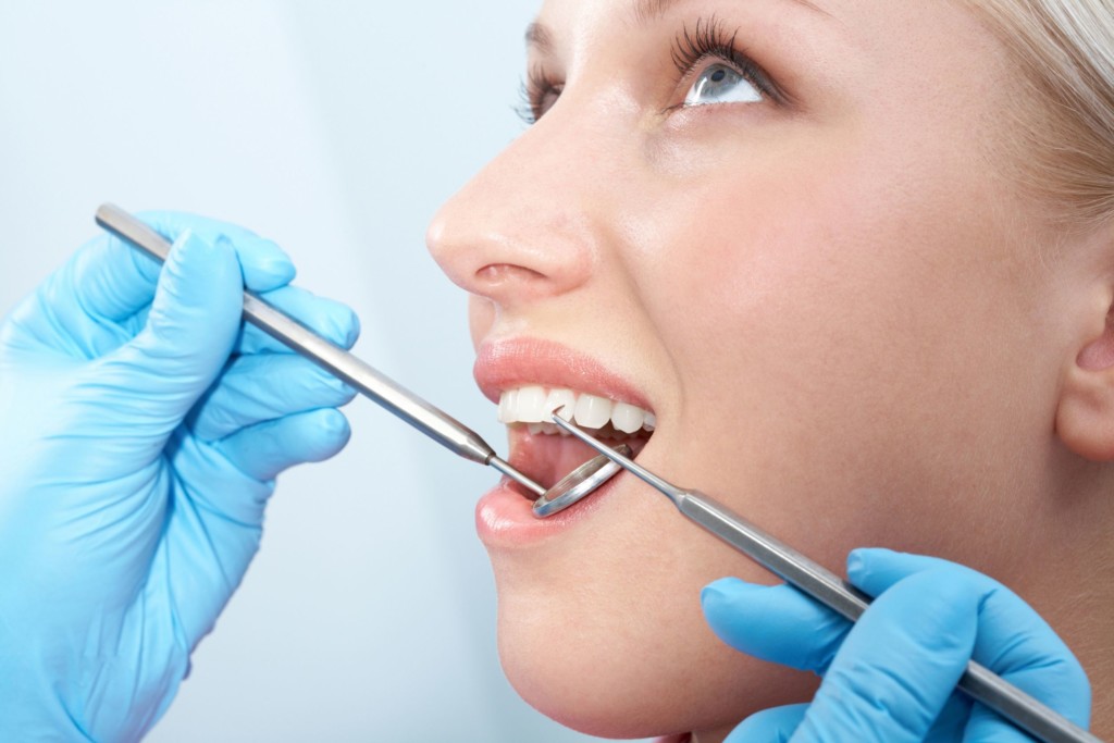 A close up of a woman's face as she opens her mouth for the dentist to inspect