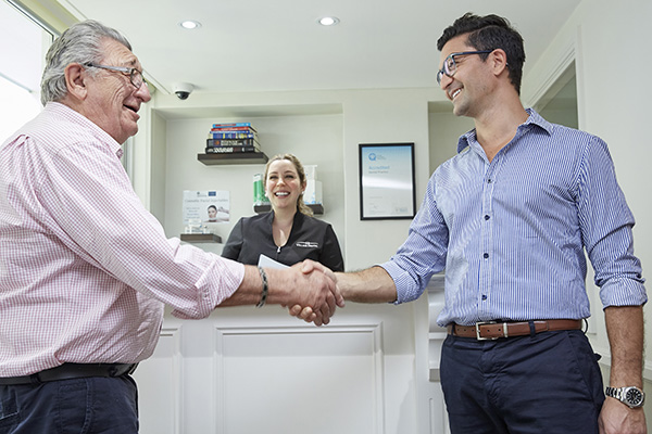 KB Village dentist shaking hands and smiling with an elderly patient