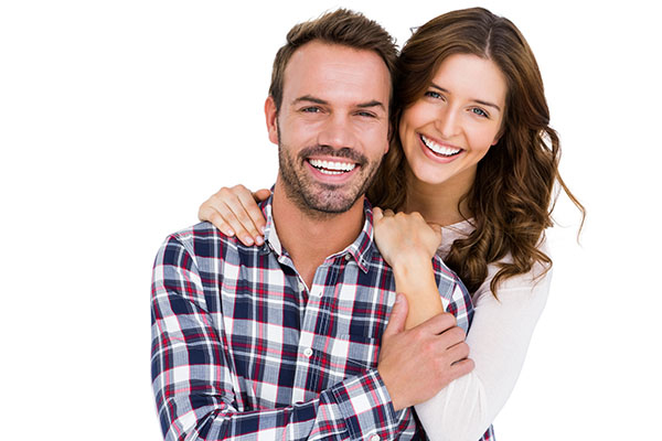 A young man and woman smiling while the woman hugs his back