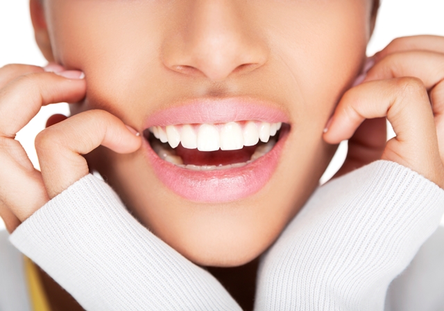 A woman opening her mouth slightly while holding the sides of her face