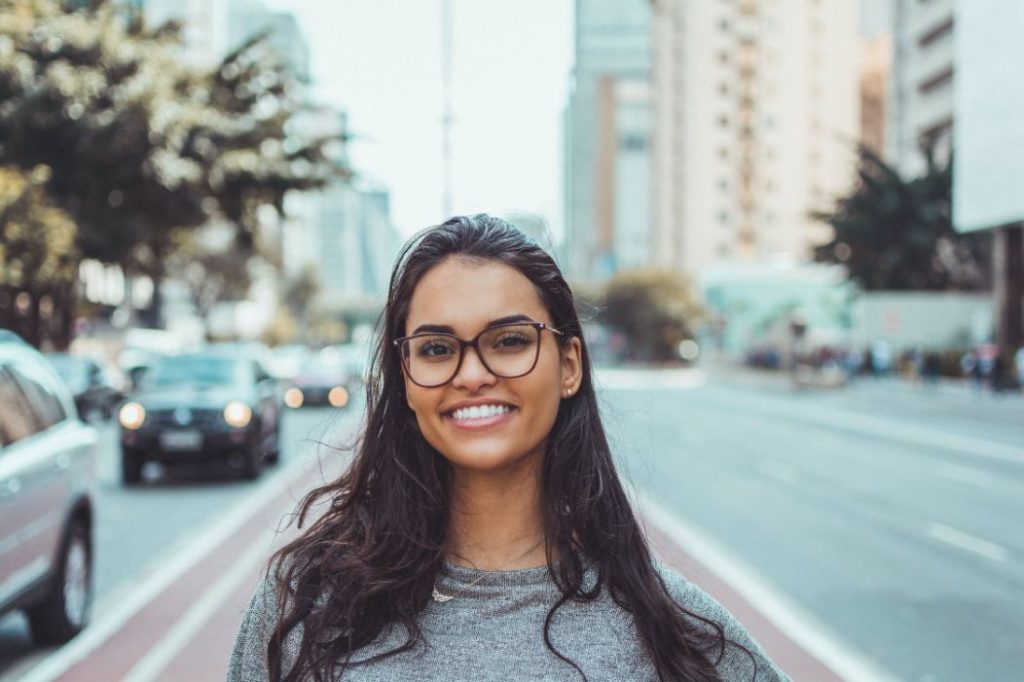 Young dark haired woman smiling in city street