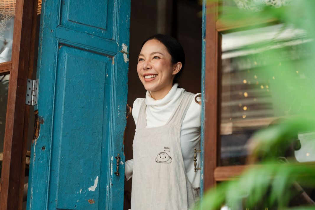 A middle aged woman smiling next to an open door