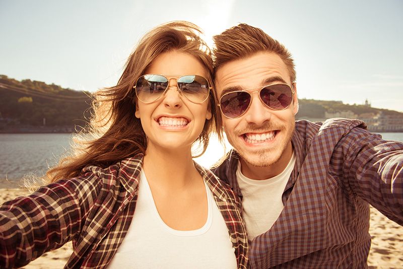 A toothy smile from a young couple wearing sunglasses
