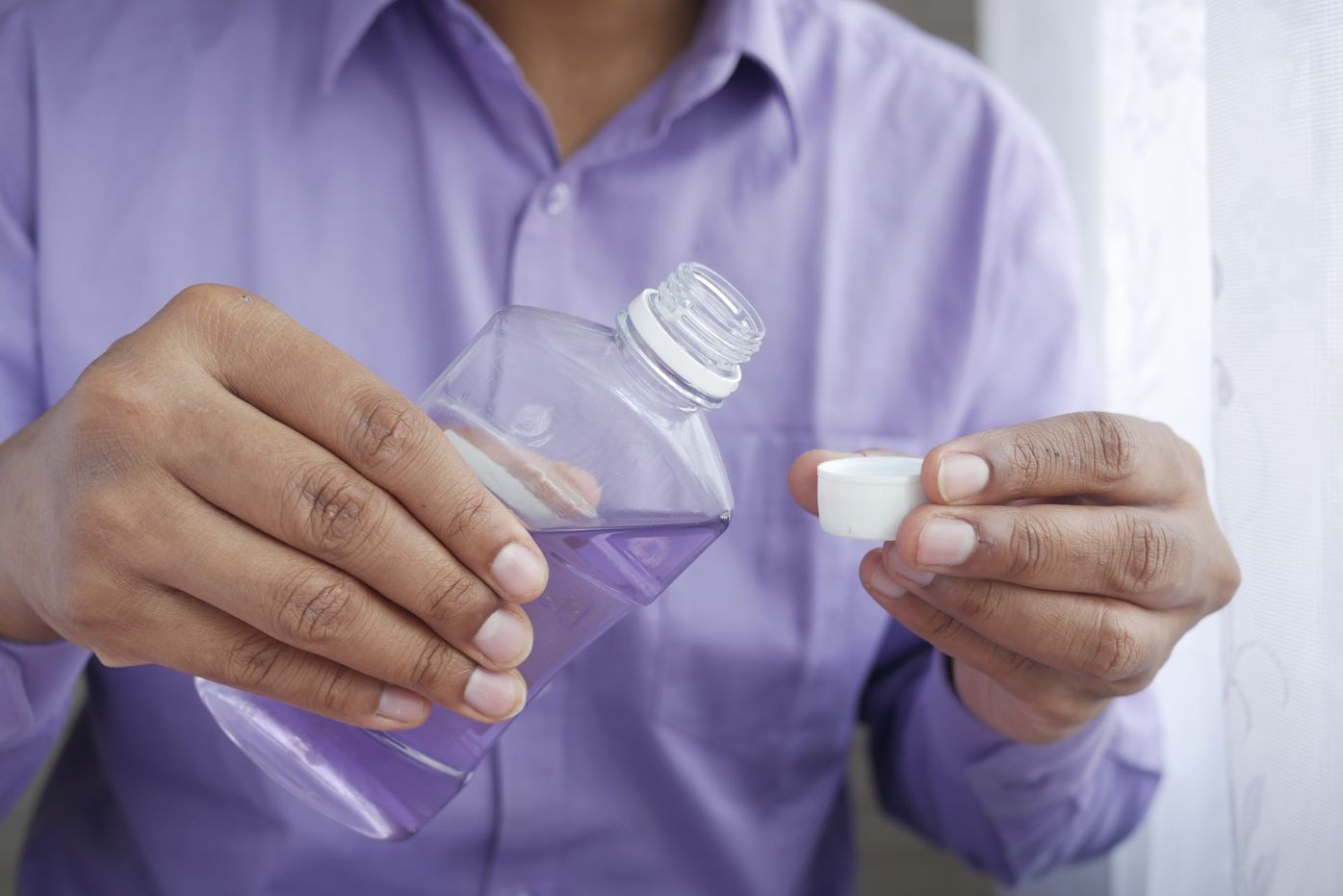 Man in purple shirt pouring saltwater from bottle