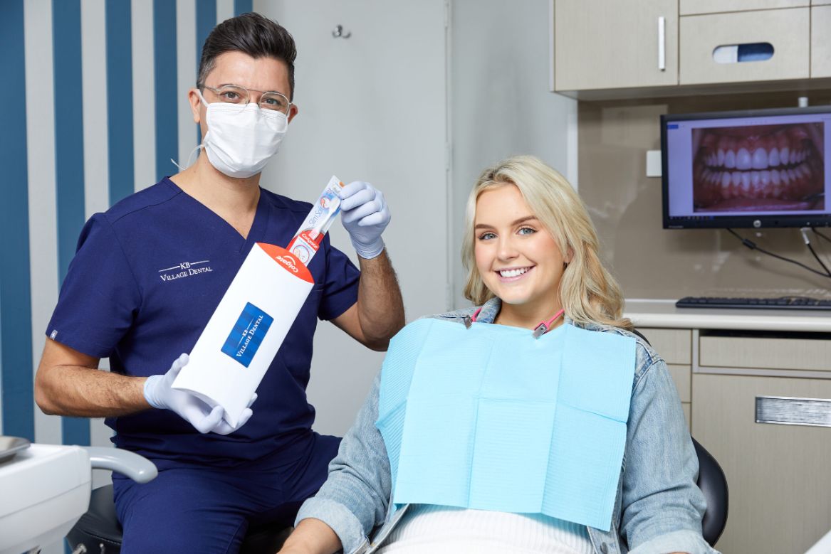 Male dentist and female patient smiling at camera