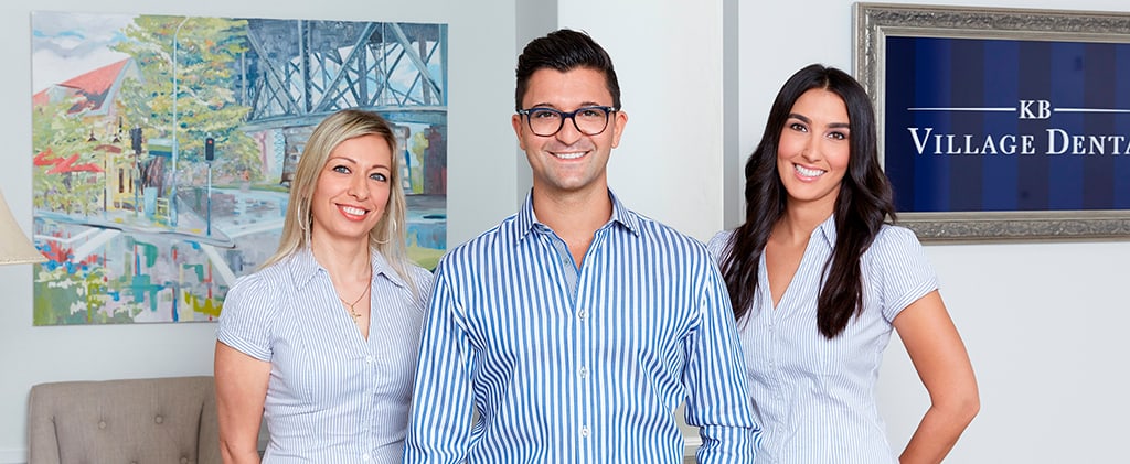 The KB Village dentist and his assistants wearing striped shirts and smiling