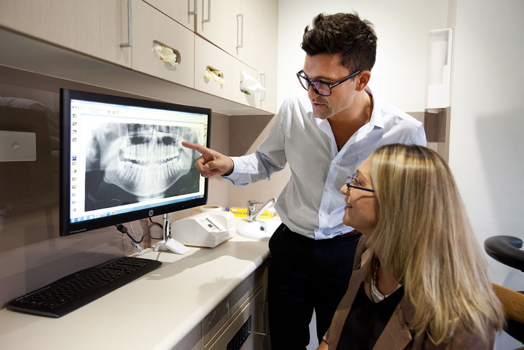 KB Village Dentist explaining an X-ray to a woman